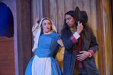 Desperate Measures-Bedtrick-5 Bella Rose in a blue and white novice nun's habit presses herself against a wood wall next to a swinging saloon ddoor and looks askance at the sherrif, with long black hair and long blue coat, hiding his face with his wide brimmed had.